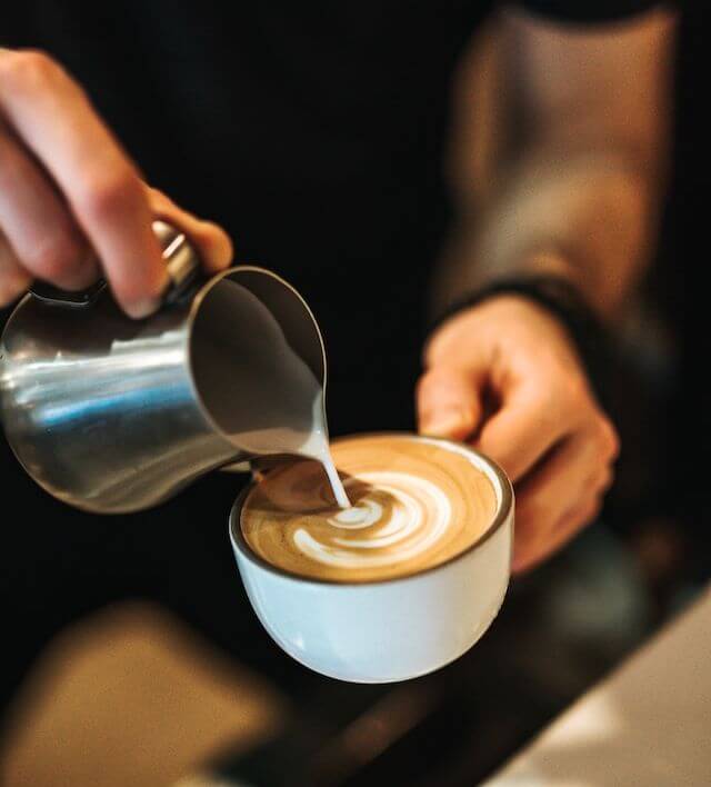 swirling cream on top of frothy coffee