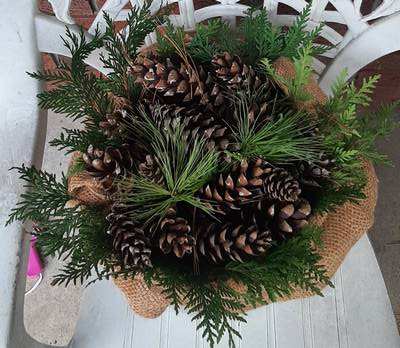 adding cedar, pine and pine cones to a galvanized bucket